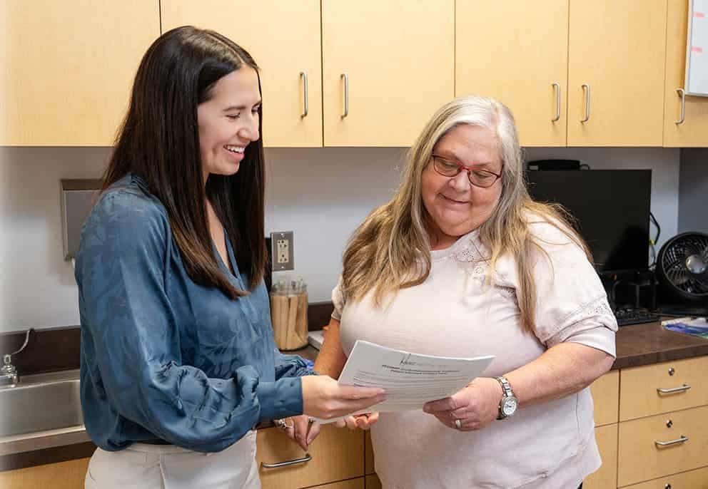 Trisha Quon, a Board-Certified Physician Assistant in Surgery showing papers to a patient